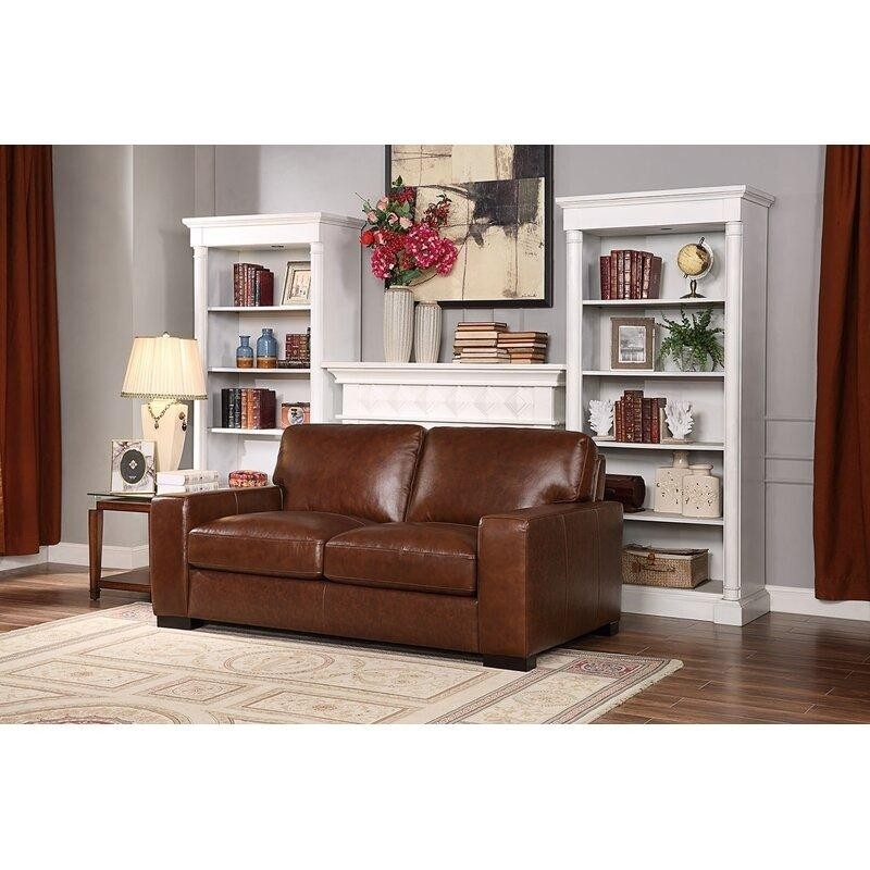 светлая гостиная с белой мебелью и камином, коричневыми кожанным двухместным диванчиком и боковом столиком в тон к дивану.jpeg