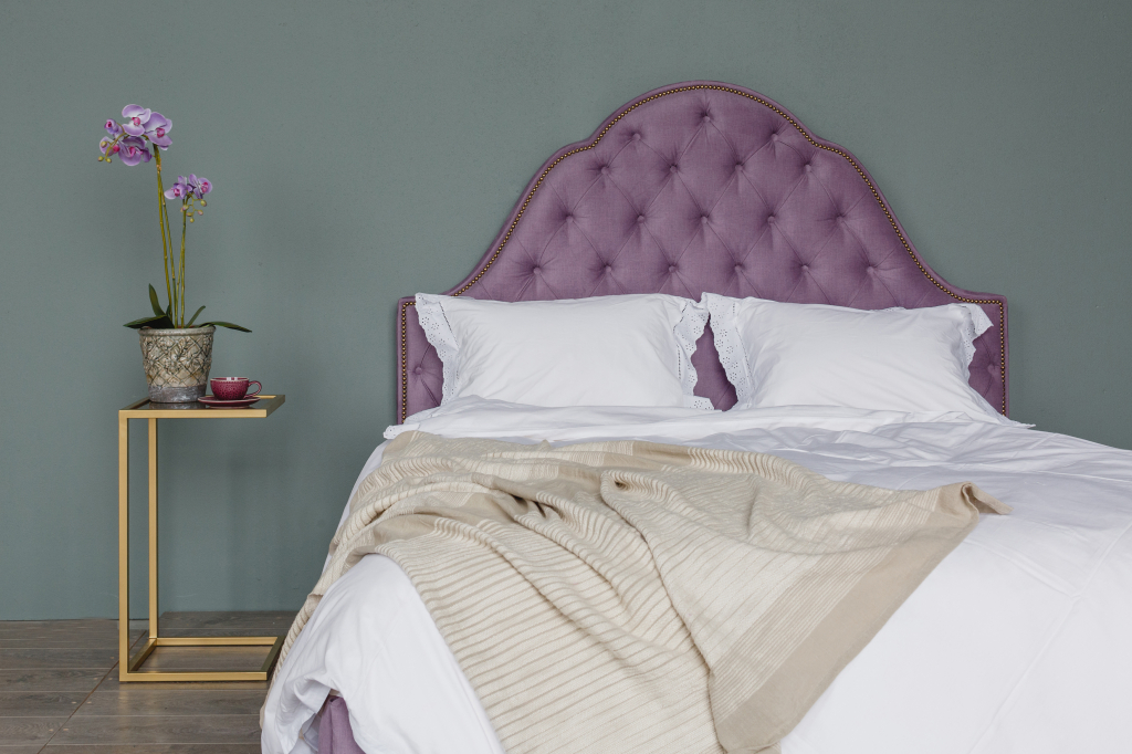 мягкая кровать лавандового цвета с фигурным изголовьем и приставной столик с металлическим каркасом и стеклянной столешницей.jpg