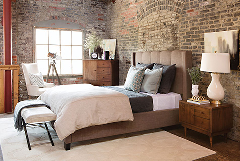 спальня в стиле лофт с кирпичными стенами и коричневой мягкой кроватью.jpg