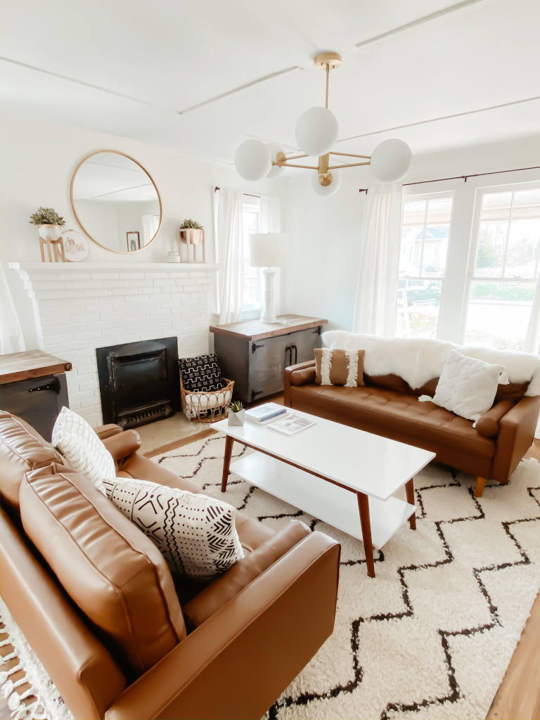 современная белая гостиная с камином, кожаными диванами и стильной люстрой