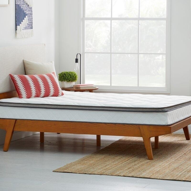 белая спальня с большим окном, деревянной кроватью, циновкой на полу и тканым панно на стене.jpeg