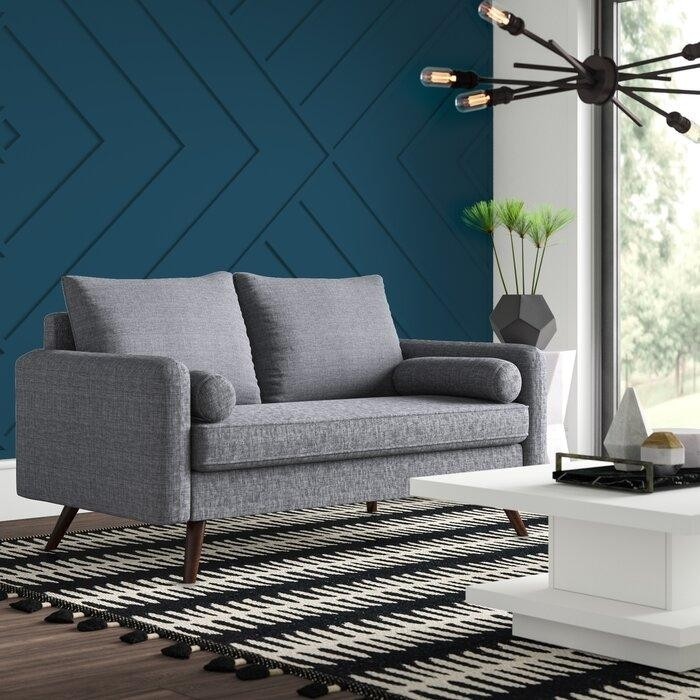 серый двухместный диван на деревянных ножках в гостиной с рельефной стеной цвета морской волны.jpeg