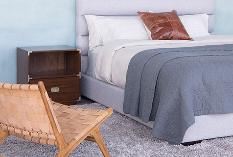 спальня с плетеным креслом, мягкой светло-серой кроватью и пушистым серым ковром.jpg