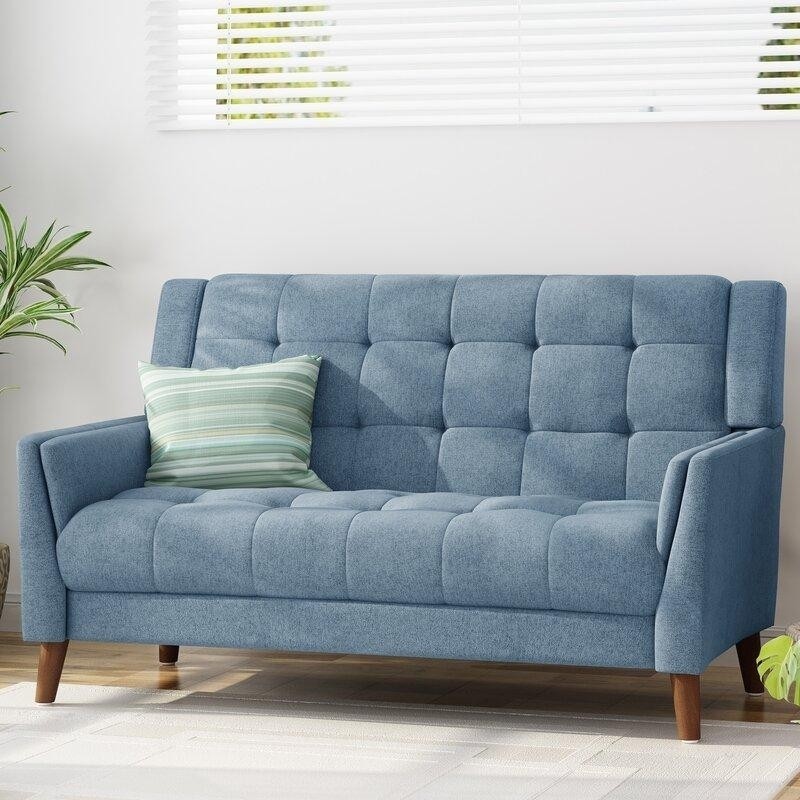 минималистичный голубой диванчик для двоих с полосатой подушкой в светлой комнате.jpeg