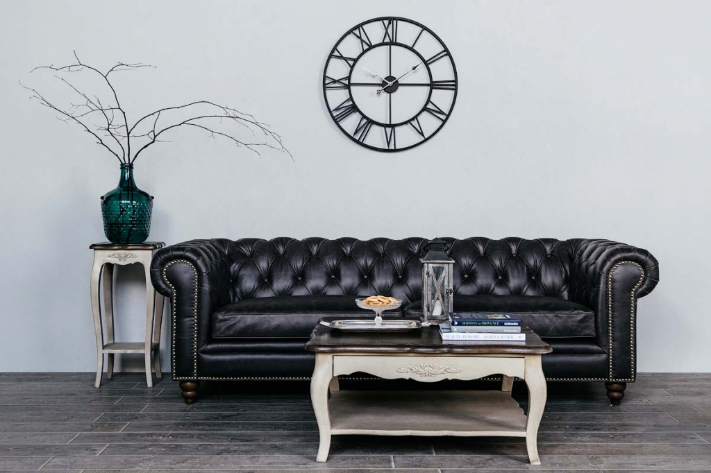 классический журнальный столик в гостиной с черным кожанным диваном и большими черными часами над диваном.jpg